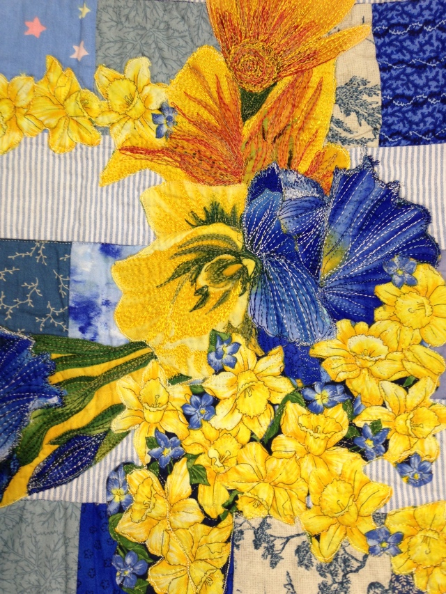 a close up showing the thread painting over top simple fussy cut flowers from print fabric. 