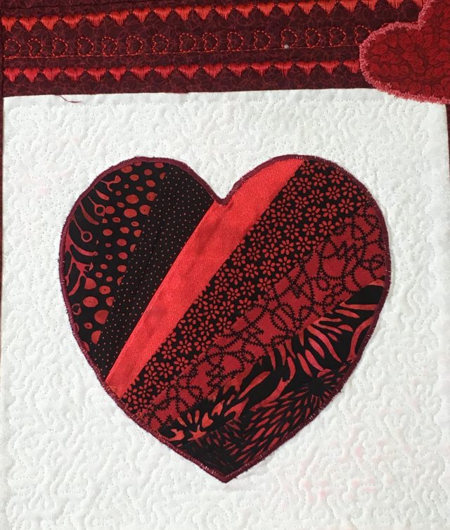 raw edge machine applique, micro stippling aroundthe heartusing Janome Digitizer MBX Ambiance quilting function + heart dec stitching above in the border